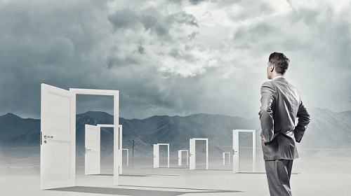 Businessman standing in front of opened doors and making decision